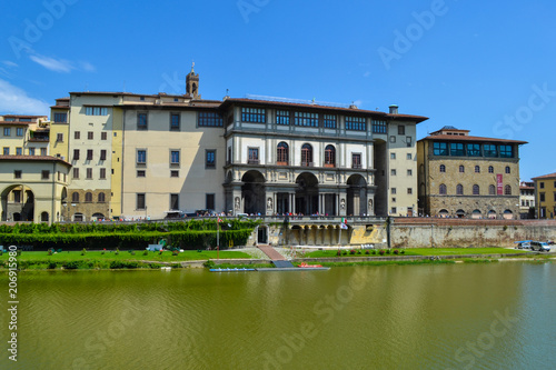View of houses and buildings through Arno river at a sunny day in summer. Florence, Italy.