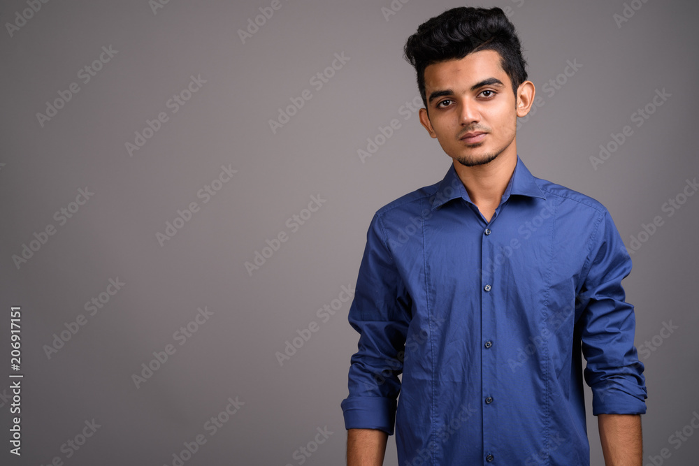 Fototapeta premium Young Indian businessman against gray background