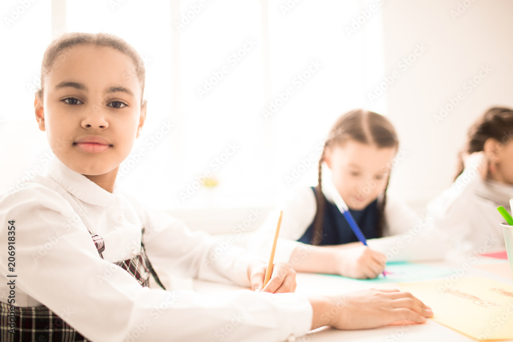 Portrait of African schoolgirl sitting at hte desk and writing Portrait of African schoolgirl sitting at hte desk and writing