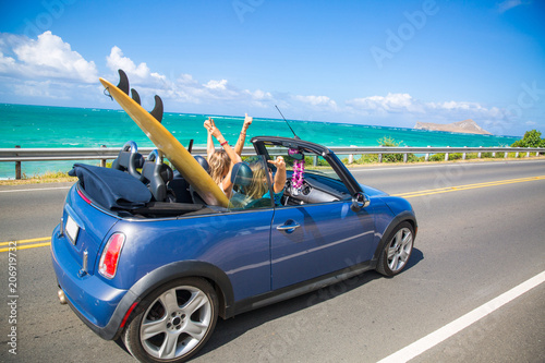Road trip travel - girls driving car in freedom. Happy young girls cheering in convertible car on summer Hawaii vacations.