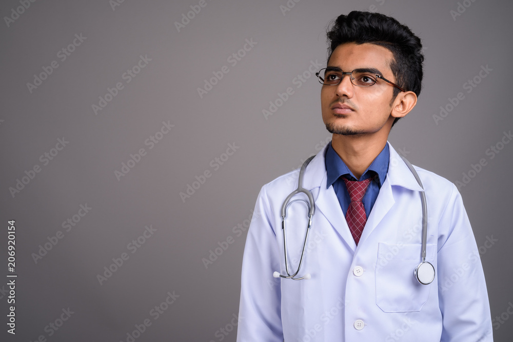 Young Indian man doctor against gray background Young Indian man doctor against gray background
