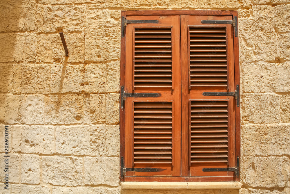 A shuttered window of a historic building with shutters.