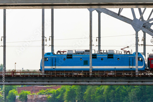 Modern light blue electric locomotive of train on bridge