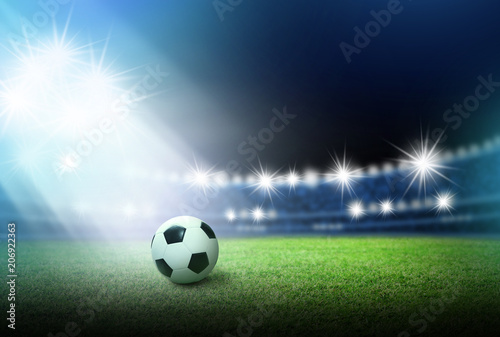 Soccer ball on green grass in stadium with spotlight