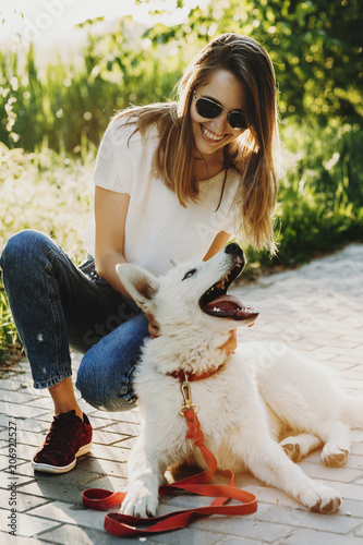 Amazing young caucasian woman in sunglasses looking at her siberian dog laughing while the dog is also laughing at her in the morning outdoor. photo