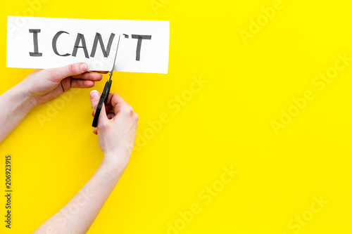 I can concept. Motivate youself, believe in yourself. Hand cut off the letter t of written word I can't by sciccors. Yellow background top view copy space