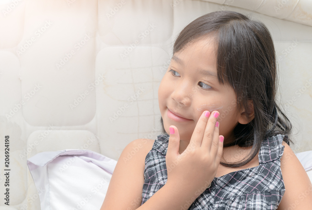cute girl applying body lotion cream on her cheek cute girl applying body lotion cream on her cheek