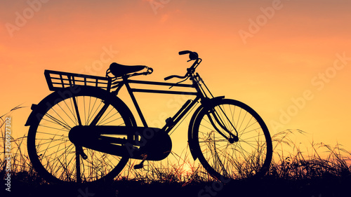 beautiful landscape image with Silhouette Bicycle at sunset in vintage tone style