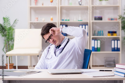 Wallpaper Mural Young doctor sitting in the office Torontodigital.ca