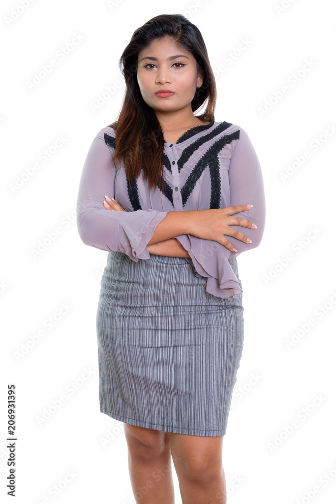 Studio shot of young fat Persian businesswoman standing with arm Studio shot of young fat Persian businesswoman standing with arm