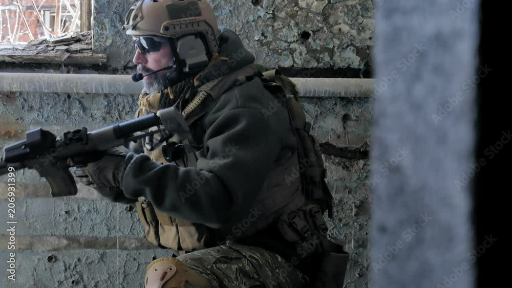 Soldiers in camouflage with a military weapon aiming through the rifle sight through the window of an old building, the military concept Soldiers in camouflage with a military weapon aiming through the rifle sight through the window of an old building, the military concept