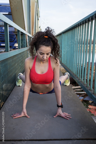 Fototapeta Naklejka Na Ścianę i Meble -  Fit young long curly dark hair girl exercise and stretch on the bridge