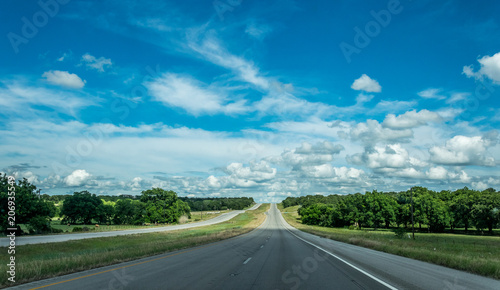 Rural road in Texas, USA. Agricultural landscape and blue sky