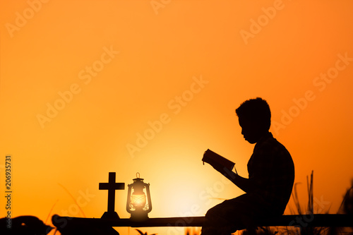 boy reading bible on wood , christian silhouette concept.