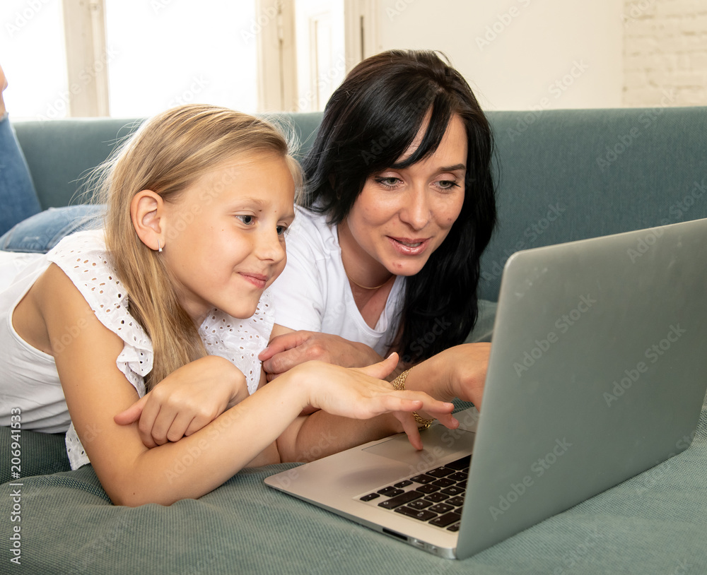 Mother and daughter smiling and having fun together playing and surfing on the internet on a laptop Mother and daughter smiling and having fun together playing and surfing on the internet on a laptop