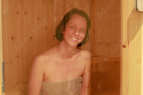 Frau lächelt durch das Fenster einer Sauna