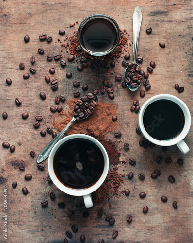 Different kinds of coffee in mug, cup and glass with spoons (wooden background)