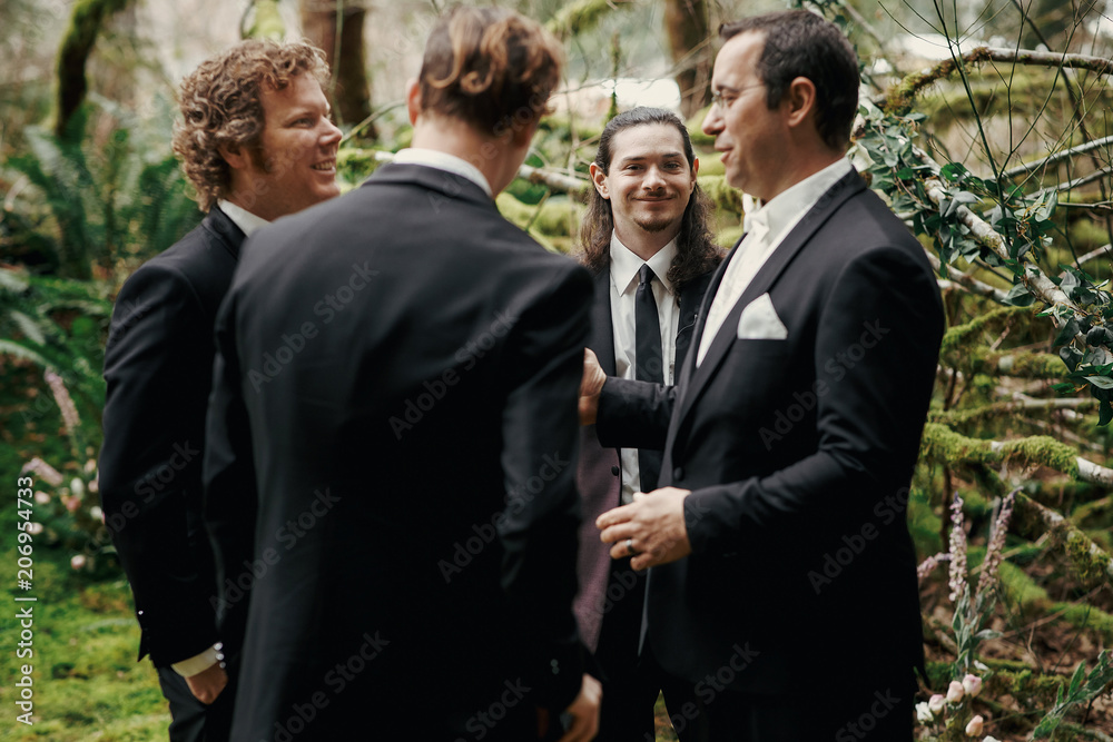 Groom and groomsmen with unusual appearane pose in the dark forest Groom and groomsmen with unusual appearane pose in the dark forest