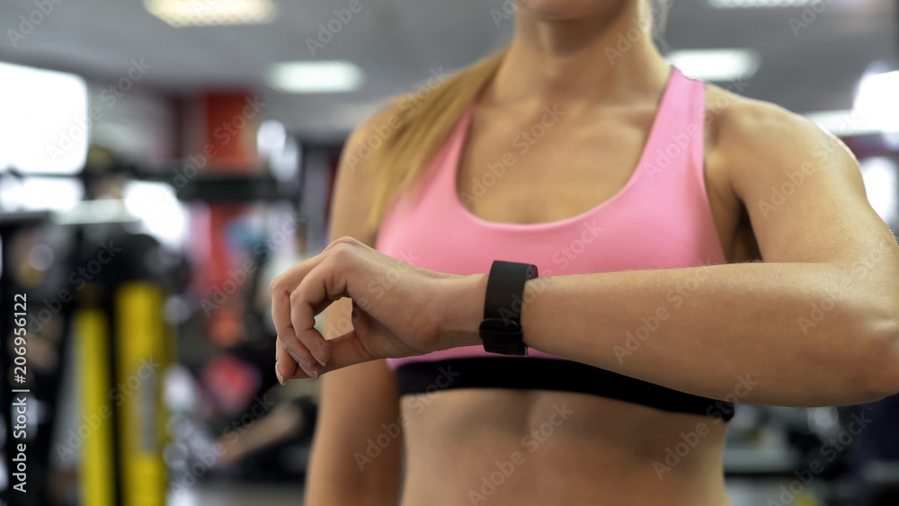 Fototapeta premium Fit lady looking at sport bracelet indicators, pulse rate and workout duration