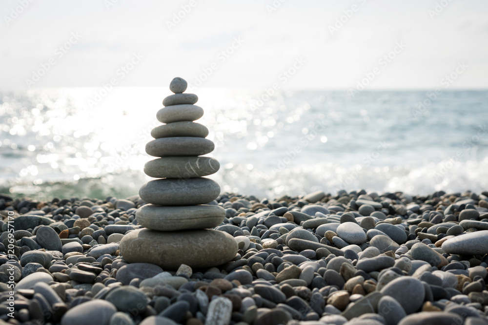 Fototapeta premium a pyramid of stones on a pebble beach against the sea and sky.