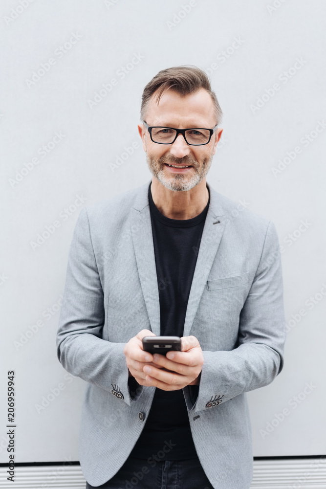 Smiling man in grey jacket using mobile phone Smiling man in grey jacket using mobile phone