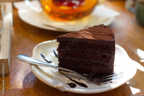Fototapeta Naklejka Na Ścianę i Meble -  A piece of dark chocolate cake with a fork and tea