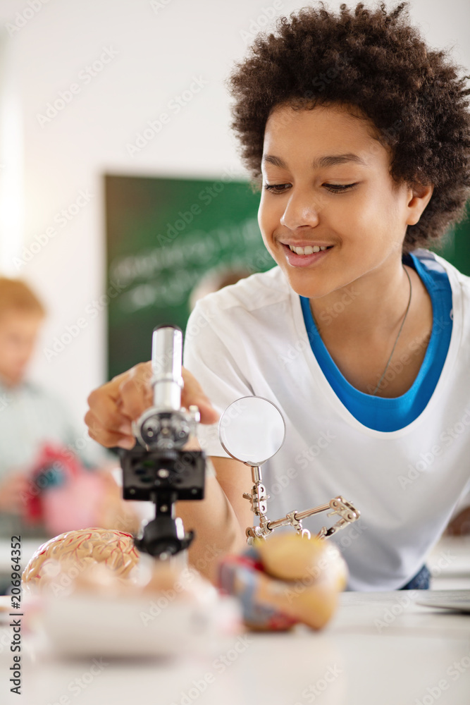 Young genius. Happy smart teenager using the microscope while studying biology Young genius. Happy smart teenager using the microscope while studying biology