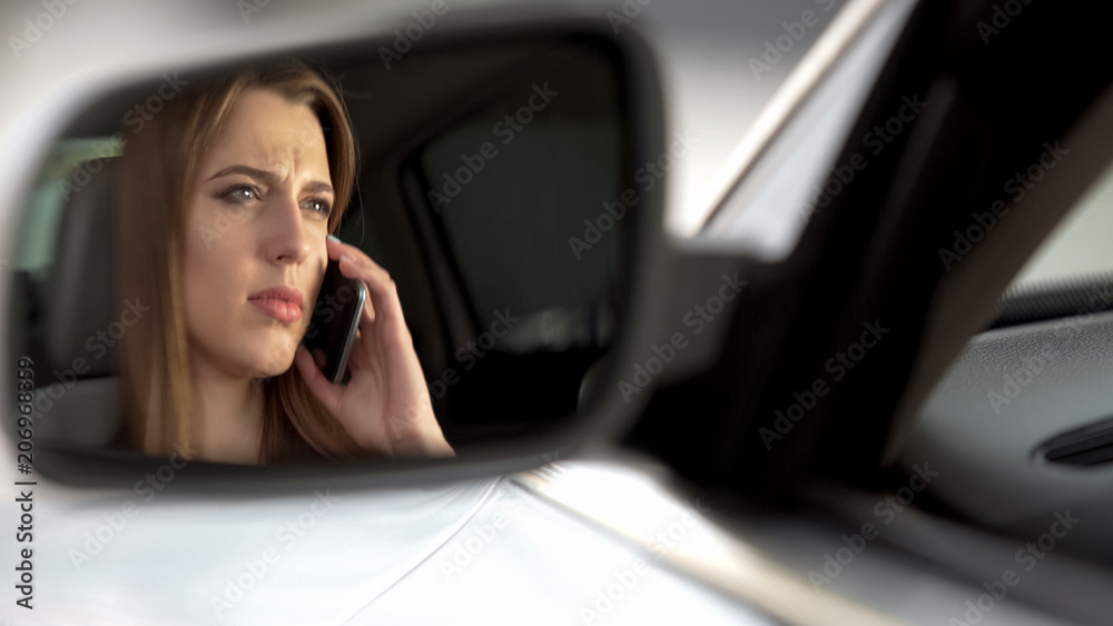 Woman talking on phone while driving, inattentive on road, rearview mirror