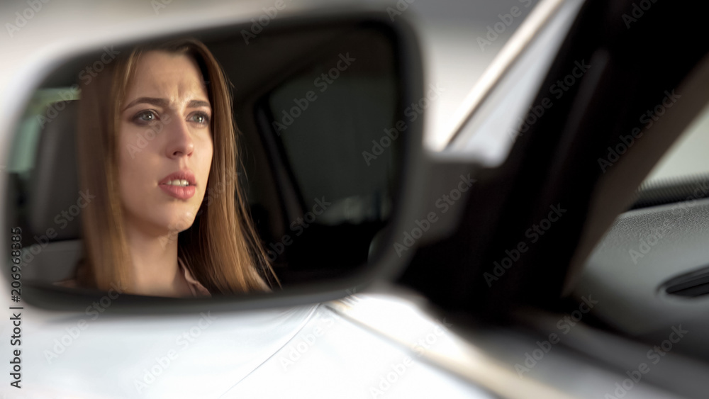 Young upset woman sitting in car and watching road, concentration and attention
