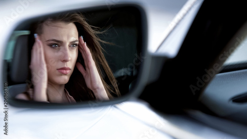 Attractive woman sitting in car, suffering from terrible headache, unhappy