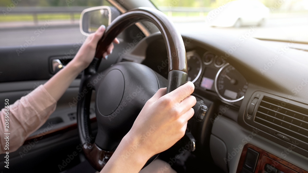 Female hands holding steering wheel, woman driving car, comfortable vehicle