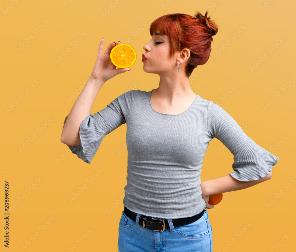 Young redhead girl holding an orange on orange background Young redhead girl holding an orange on orange background