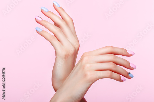 Beautiful pink and blue manicure with crystals on female hand. Close-up. Picture taken in the studio