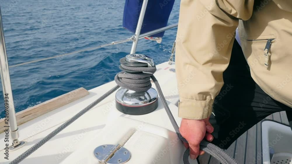 Vidéo Stock Sailor holding and tightening up grey rope winded on side ...