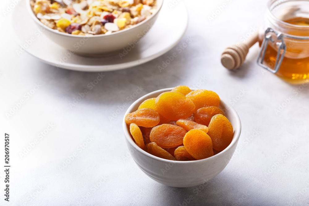 Dried Apricots In A Bowl. With Honey And Muesli. White Background. Dried Apricots In A Bowl. With Honey And Muesli. White Background.