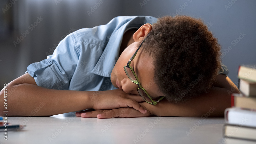 Tired pupil sleeping, sitting at desk, hard educational process, overworked boy Tired pupil sleeping, sitting at desk, hard educational process, overworked boy