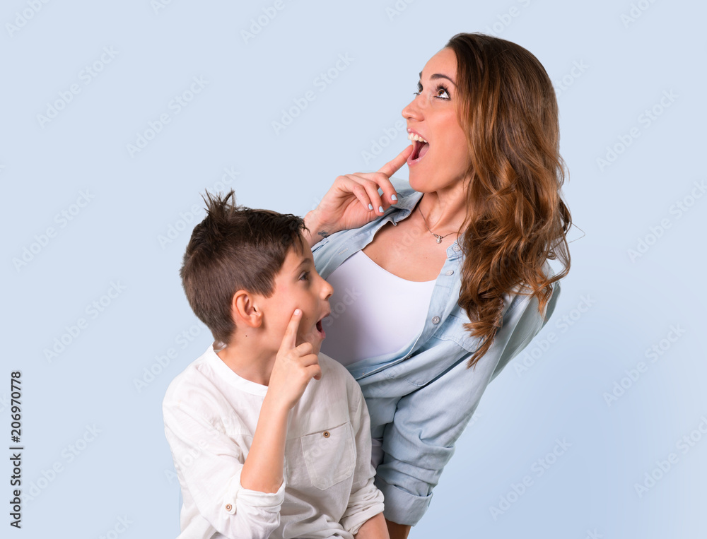 Mother and daughter standing and thinking an idea on blue background Mother and daughter standing and thinking an idea on blue background