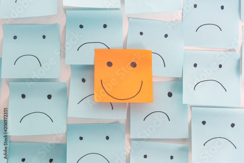 Positive Attitude and Happy Concept. Hand Drawn A Smile Face And Sad Emotion on Sticky Note Background. photo