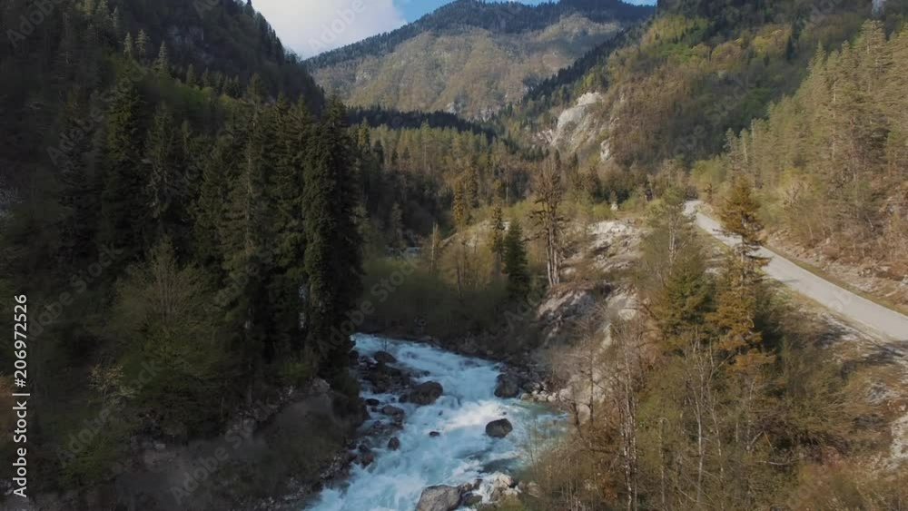 Drone slowly flying above the forest and wild river in summer. Majestic green forest and high mountains. Road and riverside. Drone slowly flying above the forest and wild river in summer. Majestic green forest and high mountains. Road and riverside.