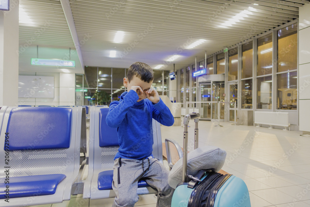© Michael - Young boy sitting alone in a corridor of airport at feeling sad mood and crying