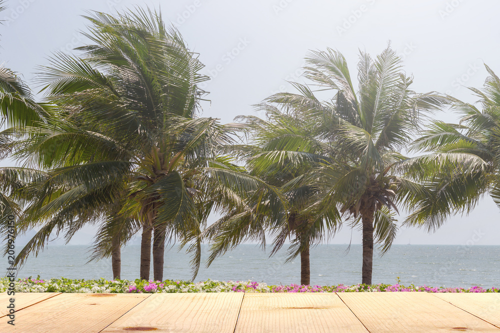 Obraz premium wooden table and palm tree at sea summer