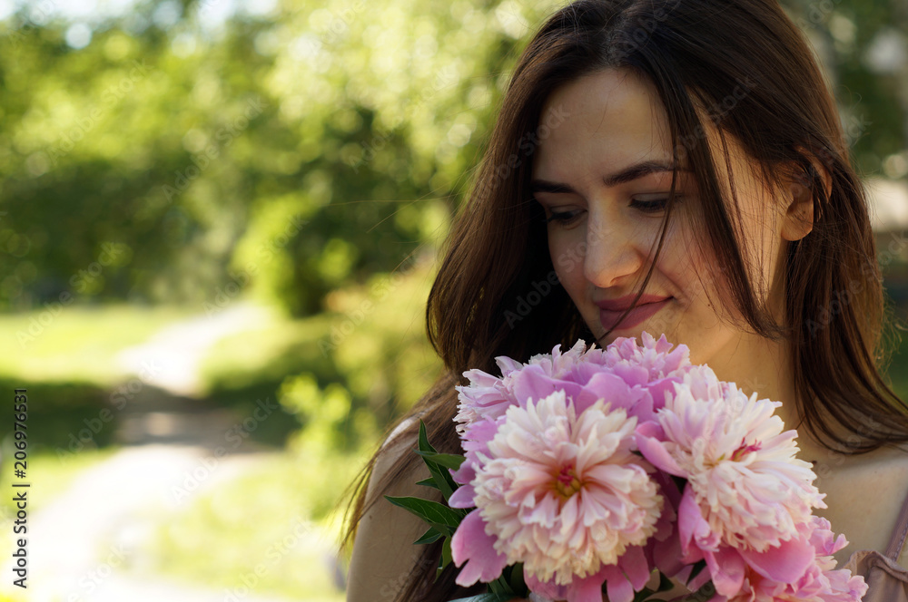 Pretty young beautiful woman on a bench with peony flowers and shining sun. Place for text Pretty young beautiful woman on a bench with peony flowers and shining sun. Place for text