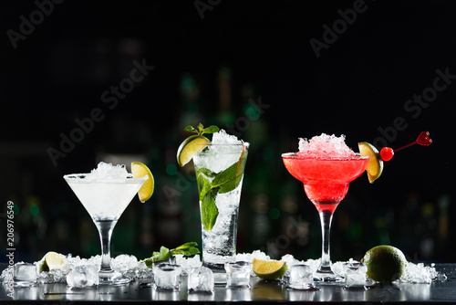 Multi-colored alcoholic cocktails with citrus in glasses of different shapes on the bar.