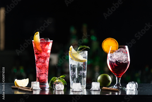 Multi-colored alcoholic cocktails with citrus in glasses of different shapes on the bar.