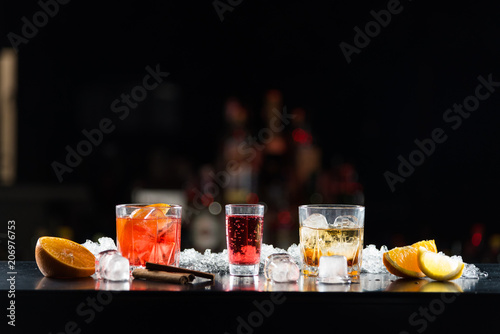 Multi-colored alcoholic cocktails with citrus in glasses of different shapes on the bar.