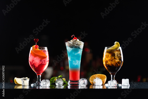 Multi-colored alcoholic cocktails in glasses of different shapes on the bar.