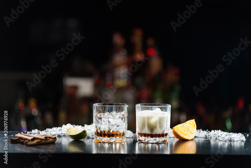Two glasses of alcoholic drinks with ice on the table. With slices of lime and orange.