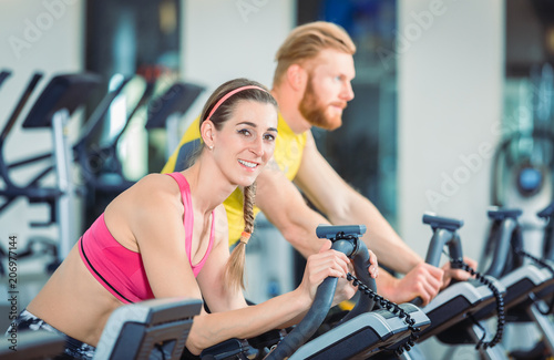 Fitness Frau und Mann beim Fahrrad fahren im Fitnessstudio 