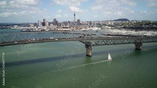 Wide drone shot white yacht sailing past Auckland harbour bridge photo