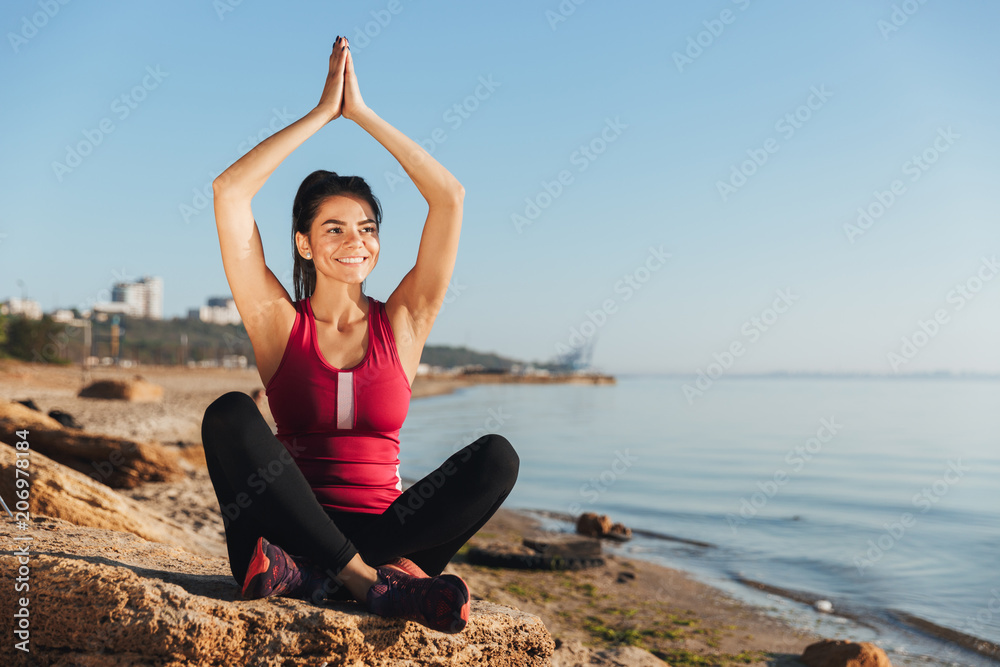 Smiling young sportswoman sitting in yoga position Smiling young sportswoman sitting in yoga position